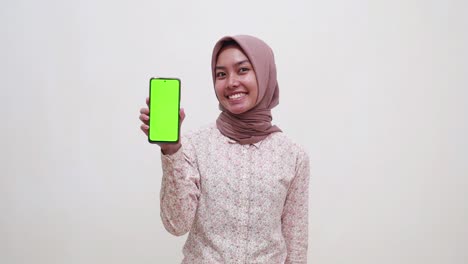 Young-asian-muslim-girl-standing-while-showing-a-blank-cell-phone-screen