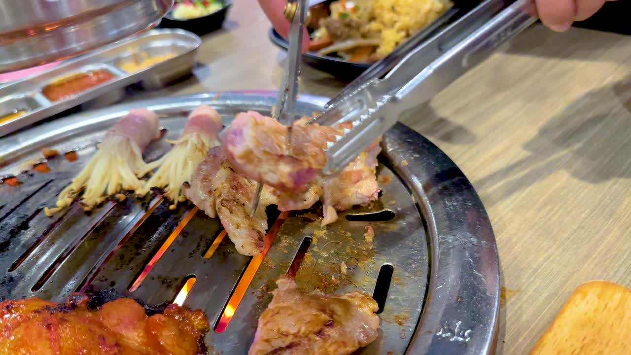 Close-up of meat grilling on a Korean BBQ in Bangkok. Vibrant colors and dynamic camera angles capture the sizzling action