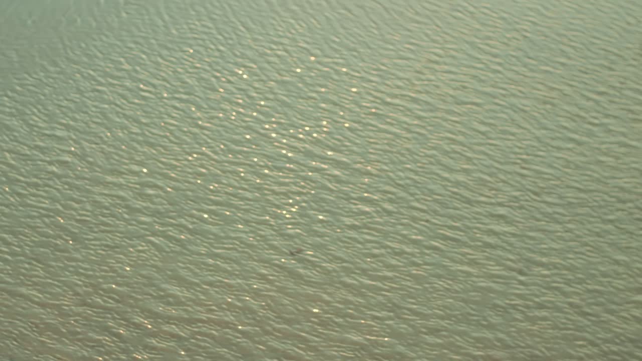 Aerial view of gently rippling water with subtle light reflections across the surface