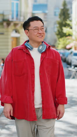 happy smiling asian middleaged man tourist walking in urban city street outdoors in summer daytime