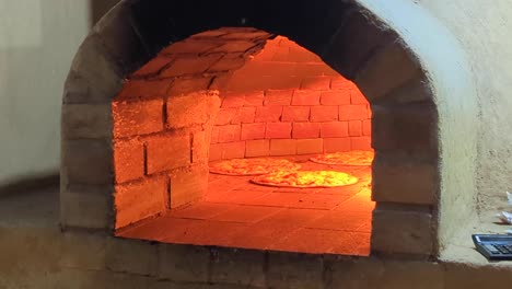 homemade authentic pizzas cooking inside a hot wood fired brick pizza oven