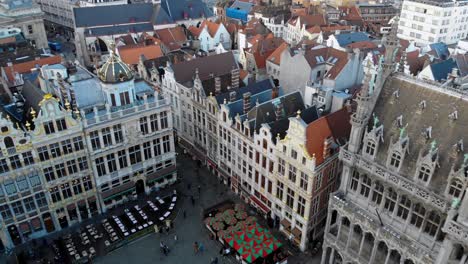 Aerial-rearward-flying-over-Maison-du-Roi,-triangle-roof-buildings-and-Grand-Place-square-on-sunny-and-cloudy-day,-Brussels-Belgium