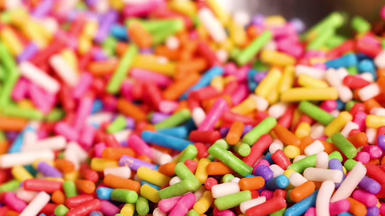A detailed view of vibrant sprinkles being scooped with a spoon, showcasing their bright colors and textures.