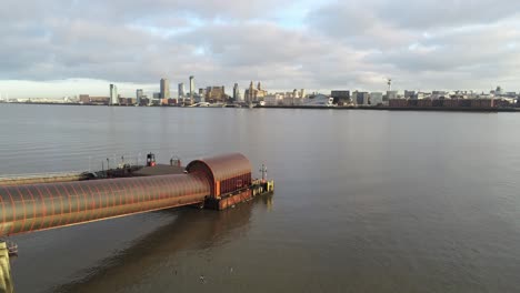 Woodside-ferry-village-terminal-aerial-rising-tilt-down-over-Birkenhead-Liverpool-harbour-skyline-as-pigeons-fly-through-shot