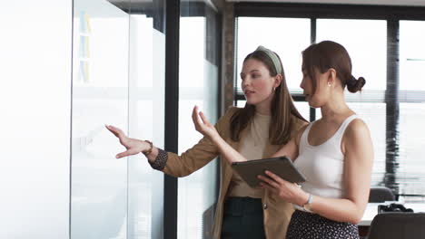 young caucasian woman and asian woman discuss business chart in an office