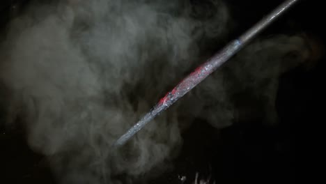 Close-up-of-blacksmith-cooling-a-iron-rod-in-water