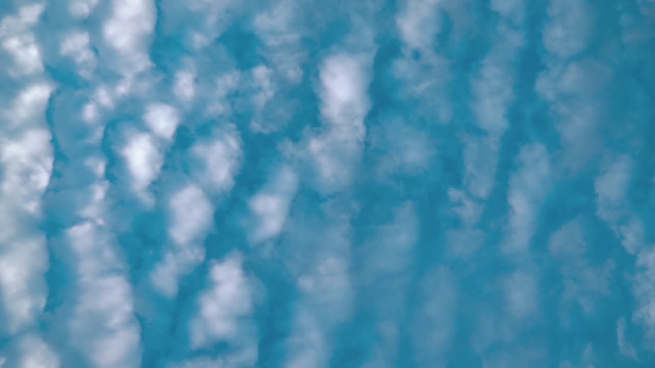 A cinematic time lapse from below, surfing white clouds, blue sky, daylight sun, 4k static video