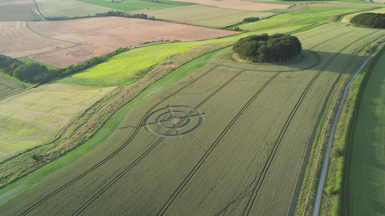 campo de trigo extraño diseño de círculo de cultivo objetivo en verde hackpen hill escena rural vista aérea retirar paisaje revelar