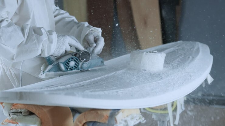 Cropped anonymous professional master polishing surfboard in workshop
