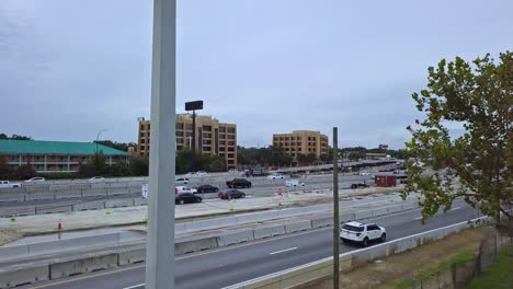 toma aérea de un dron de una carretera concurrida que muestra el cierre de la luz de la calle en primer plano con la intersección del paso elevado del puente, el tráfico vehicular, la zona de construcción de carreteras, el equipo pesado, la grúa en el fondo