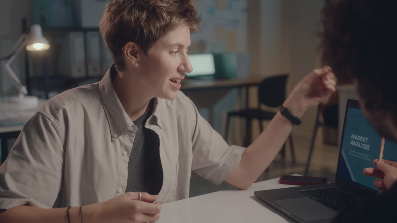 Woman Discussing Business Charts with Coworker in Office at Night