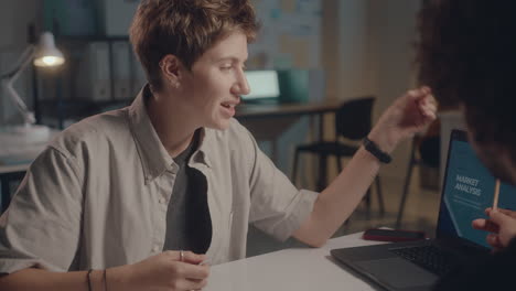 woman discussing business charts with coworker in office at night