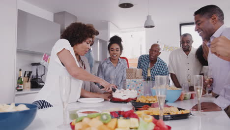 Familia-Negra-De-Tres-Generaciones-Pararse-Alrededor-De-Una-Mesa-Mientras-La-Madre-Corta-El-Pastel-En-La-Fiesta-De-Cumpleaños