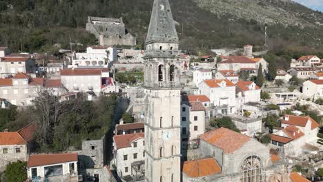 aerial pullback away from perast church reveals old town on typical day in montenegro