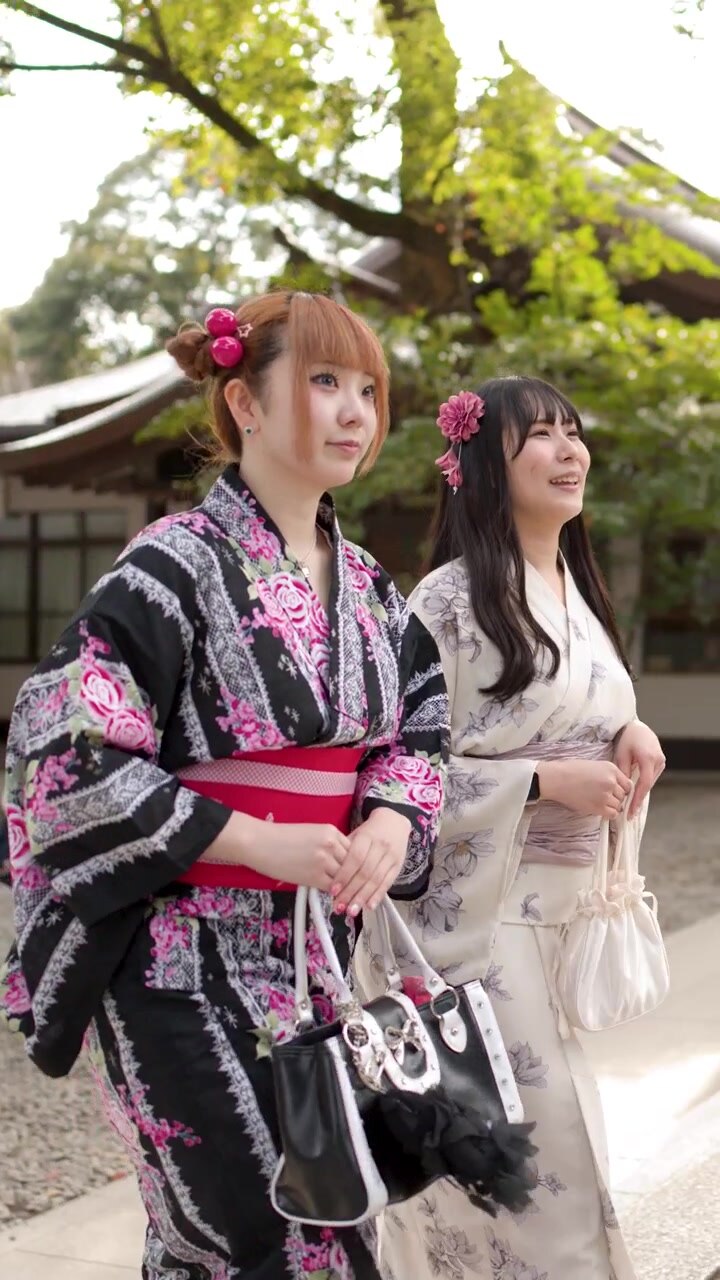 Due giovani donne in yukata tradizionale giapponese che camminano in un giardino di un tempio
