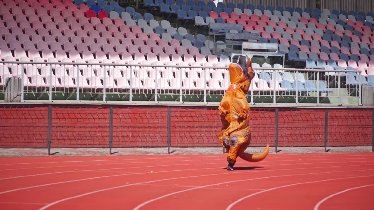 Inflatable dinosaur on stadium. Man in dinosaur costume on stadium