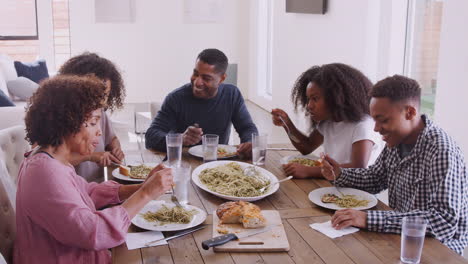 vista elevada de una feliz familia negra sentada en la mesa comiendo juntos y hablando, de cerca