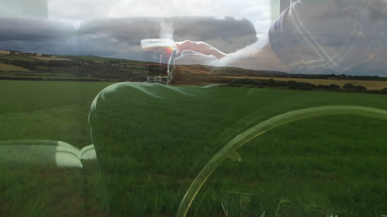 Holding steaming cup, hand over lush green field and rolling hills