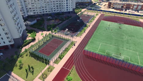 Vista-Aérea-De-Niños-Jugando-En-El-Campo-Deportivo-En-La-Zona-Residencial-Del-Patio.