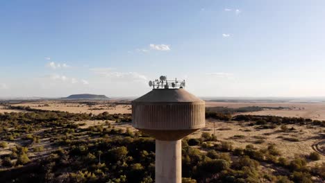 drone drop down shot of a broadcast tower in a rural area on a sunny day