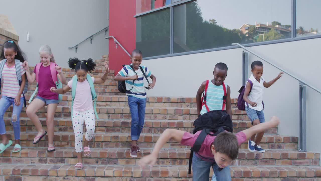 배 ⁇ 을 입고 웃고 학교에서 아래층으로 달리는 다양한 학교 아이들의 그룹