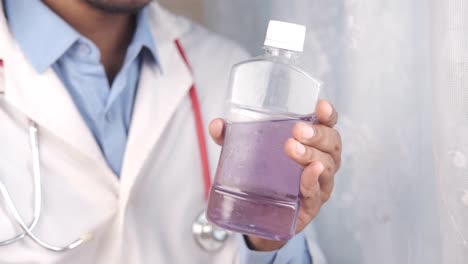 médico con una botella de líquido púrpura