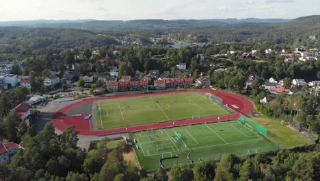 Luftaufnahme-Der-Stadt-Kragero-Mit-Sportstadion-In-Norwegen---Drohne-Fliegt-Vorwärts