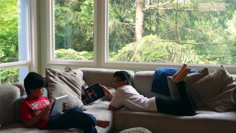 siblings using digital tablet in living room 4k