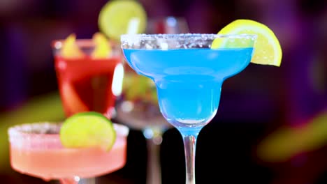 a vivid blue cocktail with a lemon slice, set against colorful blurred backgrounds, highlighting its refreshing appeal