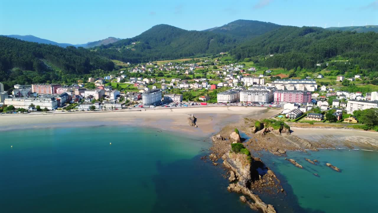 Aerial view of a coastal town with a beach and mountains