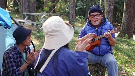 happy asian family, father and children, camping and singing together at campsite