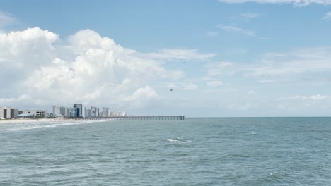 Myrtle-Beach-pier-with-hotels-and-ocean-waves