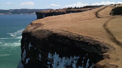 A-drone-shot-of-a-lighthouse-with-ice-clinging-to-the-nearby-cliffs