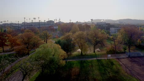 Drone-descending-over-a-public-parc-on-a-autumn-sunny-morning