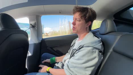 people in a tesla model 3 back seat