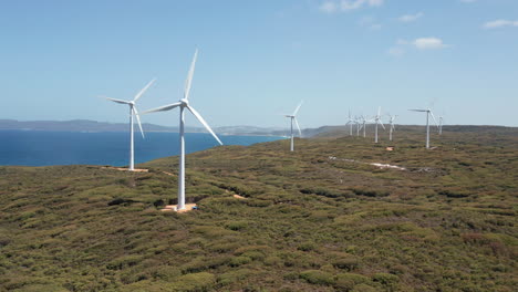 Aerial-view-of-wind-power-generators,-on-the-coastline-of-Albany,-sunny-day,-in-Australia---tracking,-Drone-shot