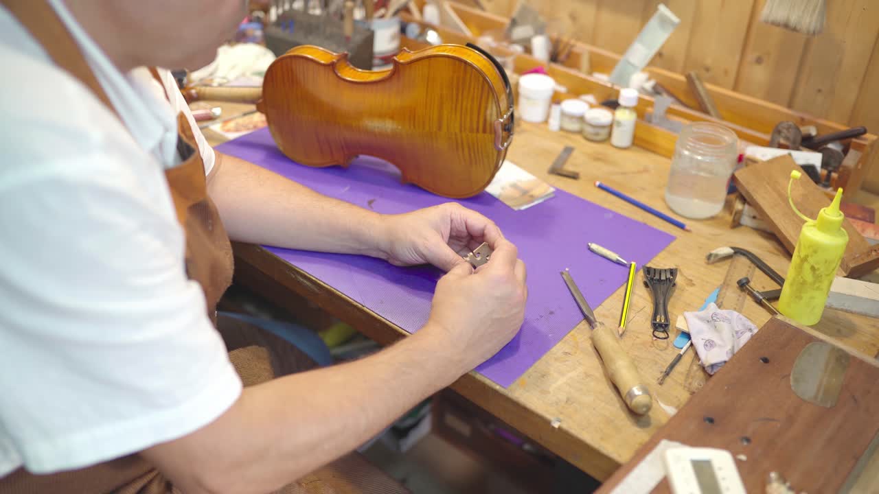 luthier anónimo con puente de violín en el taller