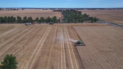 Amplia-Vista-Aérea-De-Una-Cosechadora-Trabajando-En-Un-Campo-De-Trigo-Cerca-De-Yarrawonga-Con-Equipo-Agrícola-Más-Allá