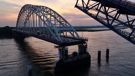 the steel bridge over the noord river descending as sunsets in the distance