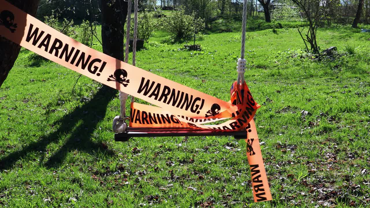 Warning sign on ribbon on swing
