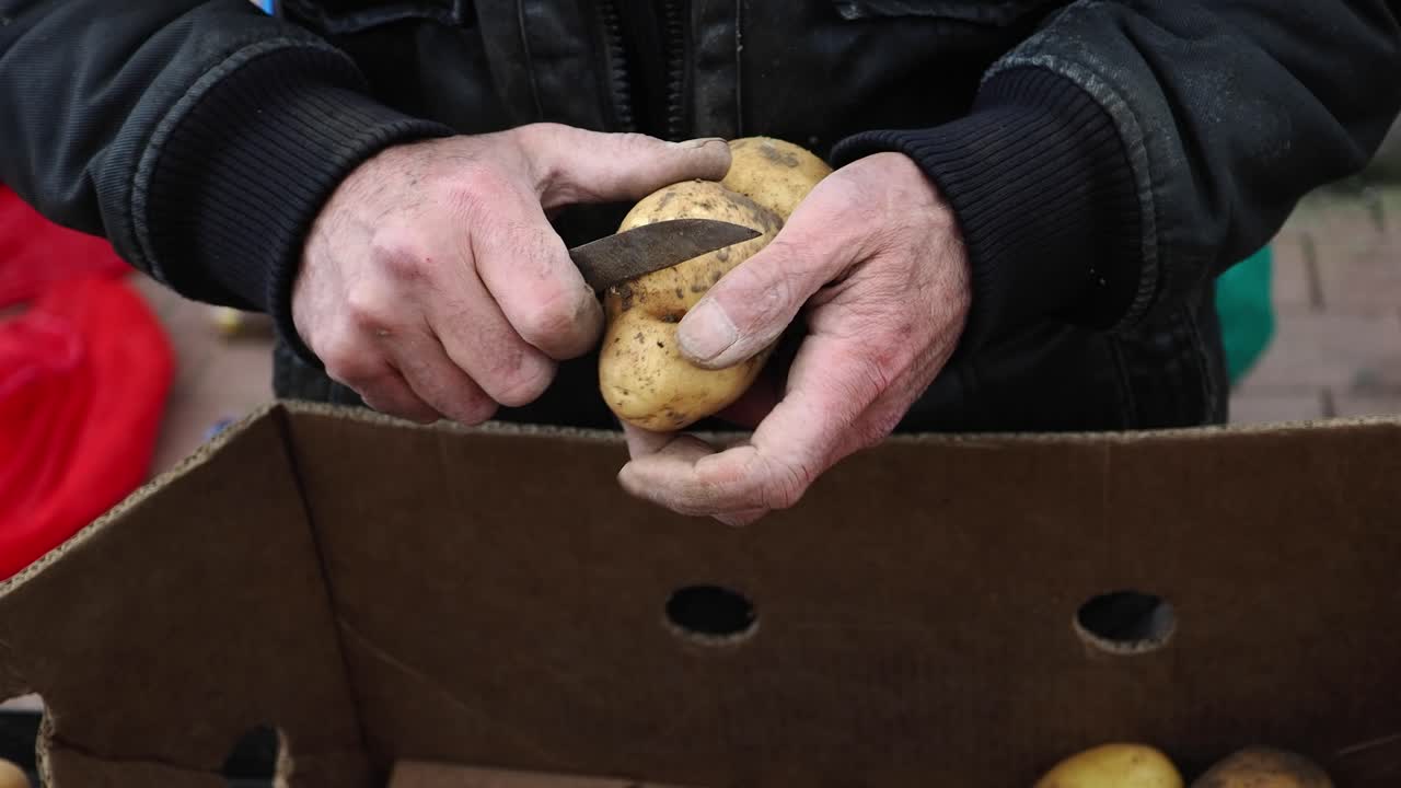 Primo piano di mani che pelano patate crude con un coltello
