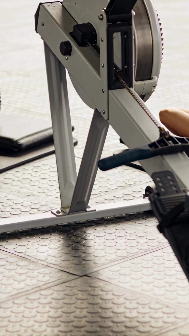 Video vertical: Usuario de gimnasio tirando del mango y realizando remadas en una máquina para entrenamiento cardiovascular.