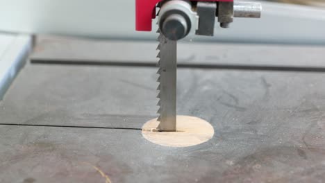 slow push in towards blade on bandsaw in toymaking workshop