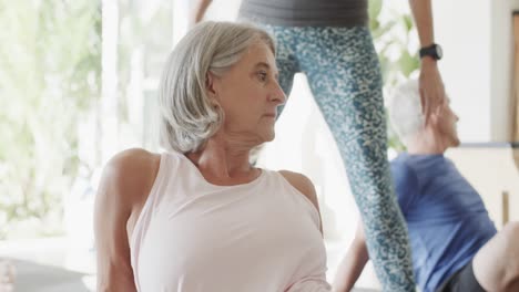 caucasian seniors practicing pilates with female coach in sunny room, unaltered, in slow motion