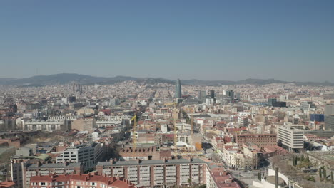 Adelante-Vuelan-Por-Encima-De-Los-Edificios-En-La-Ciudad.-Grúas-De-Torre-Alta-En-El-Sitio-De-Construcción-En-El-Distrito-Urbano.-Barcelona,-España