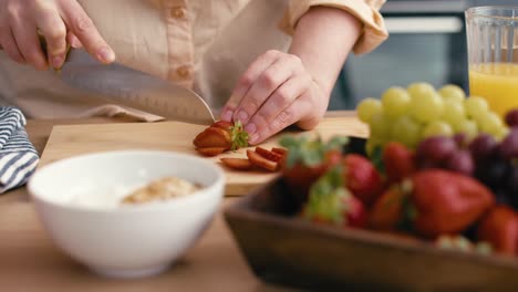 Woman-cutting-strawberries-into-slices-for-a-dish.