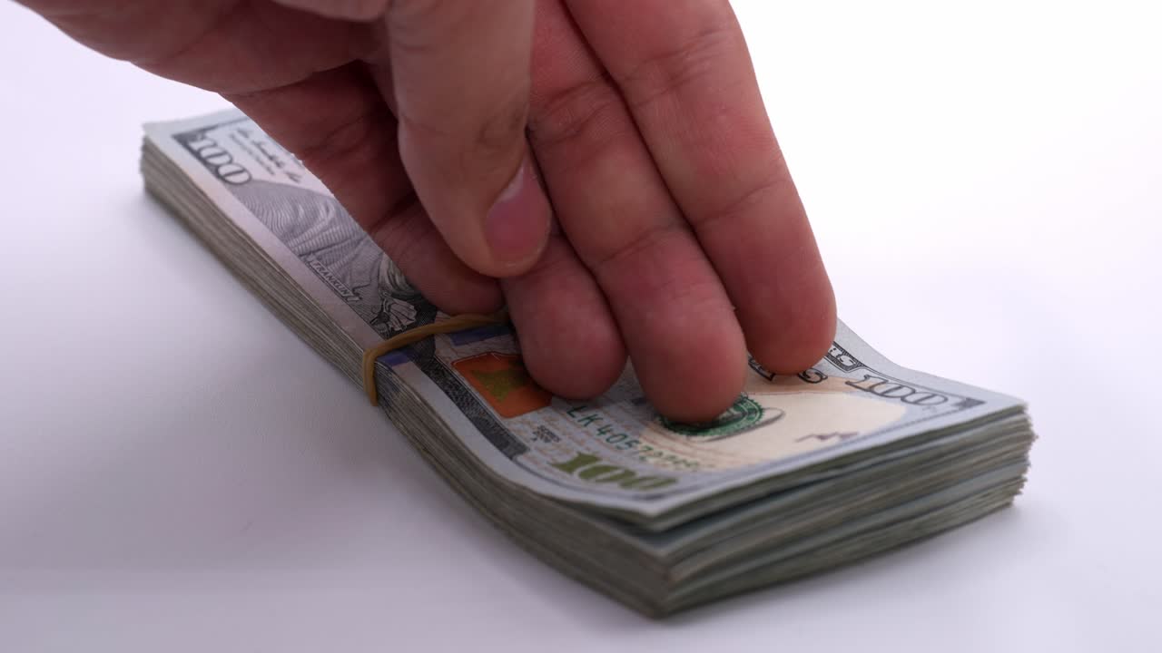 Person handling a stack of hundred-dollar bills in slow motion