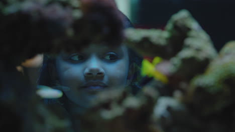 happy little girl at aquarium looking at fish curious child watching colorful sea life swimming in tank learning about marine animals at oceanarium