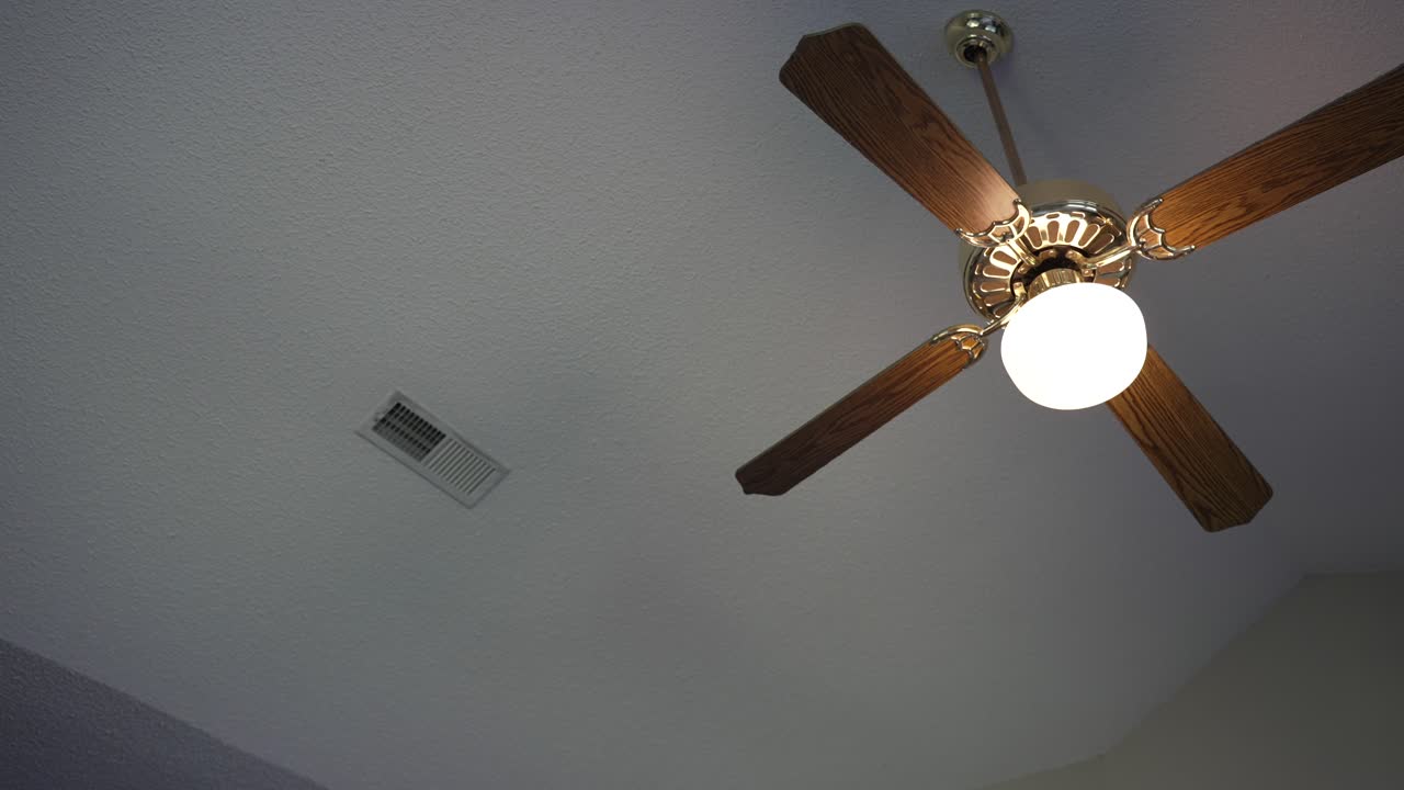 Old fashion wooden ceiling fan mounted from vaulted popcorn ceilings next to an air conditioning vent
