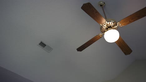 old fashion wooden ceiling fan mounted from vaulted popcorn ceilings next to an air conditioning vent